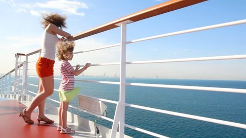 young mother and little daughter stands on deck of cruise ship