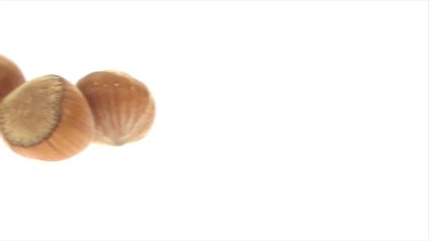 Panning right to left of three in-shell filberts on white background. This video was shoot using custom light set up with additional custom build underneath light system to eliminate shadows.