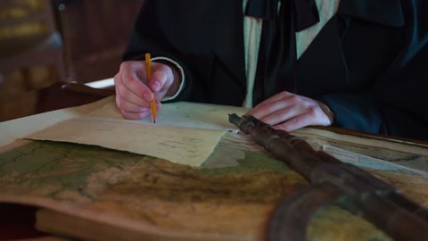 Man drawing new map. Close up slow motion RAW footage of a man drawing a new map from the old one in the medieval time on the historic desk.