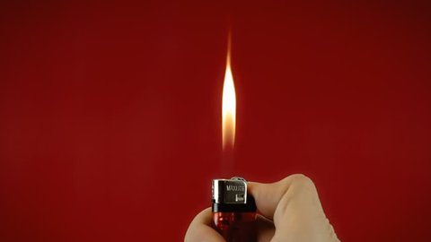 Operating a cigarette lighter. Colorful close-up shot on red background.
