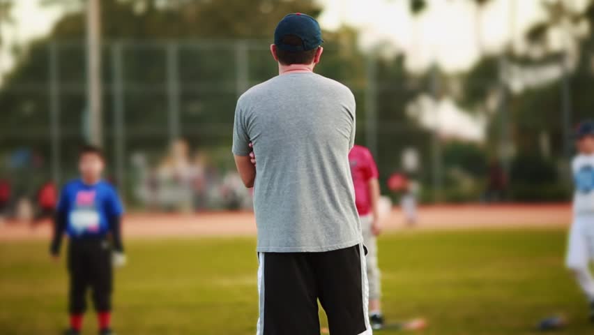 Unrecognizable male coaching kids during practice at a Baseball Field