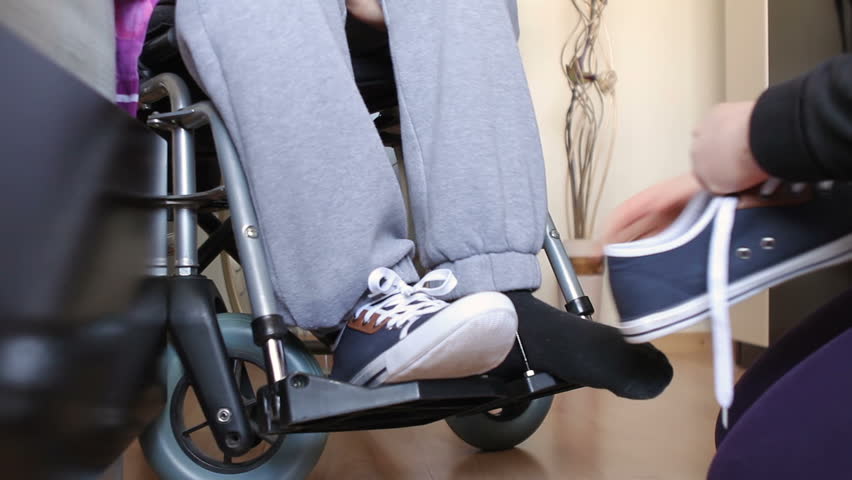 Helping a disabled young man in wheelchair get dressed. | Shutterstock HD Video #9135566