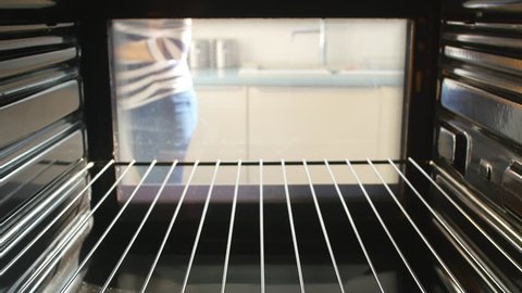 Woman opens door of oven before putting savory pie inside to cook. Shot on Sony FS700 at a frame rate of 25 fps Stock Video