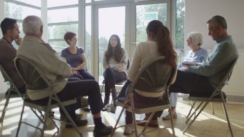 4K People in group therapy session talk about their problems in sunlit room