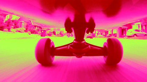Riding a dayglo skateboard down an urban street. Shot with a GoPro Hero camera. Colorized pink and lime green. Toronto, Ontario, Canada.  Stock video