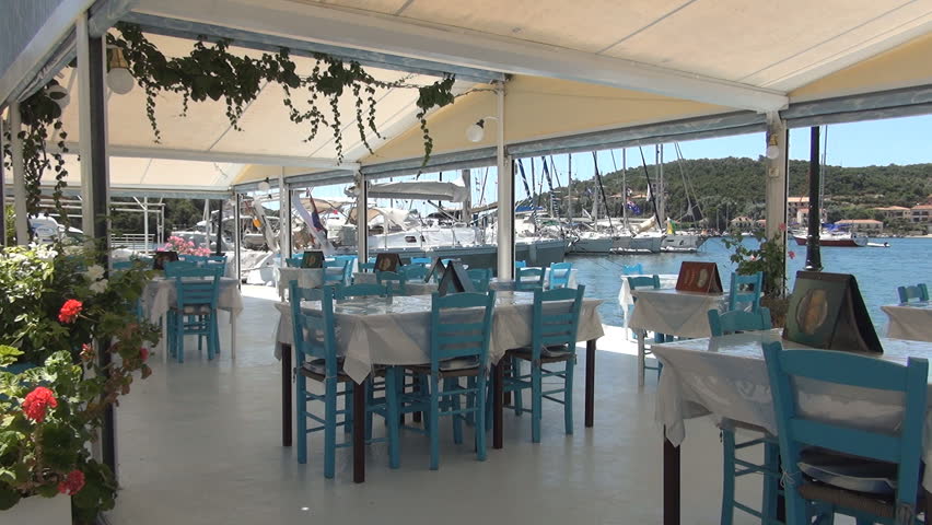 GREECE, LEFKADA PORT, JULY 17, 2014: Traditional restaurant situated in a harbor near sail boats. Romantic dinner place for summer holiday tourists.