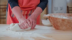 Final kneading the bough to make home make bread . Close up slow motion RAW footage of a woman kneading the dough on the wooden table to make home made bread.