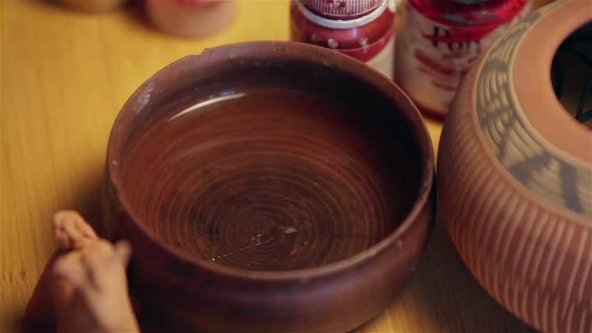 Artist wash his brush of white paint in a bowl with water.