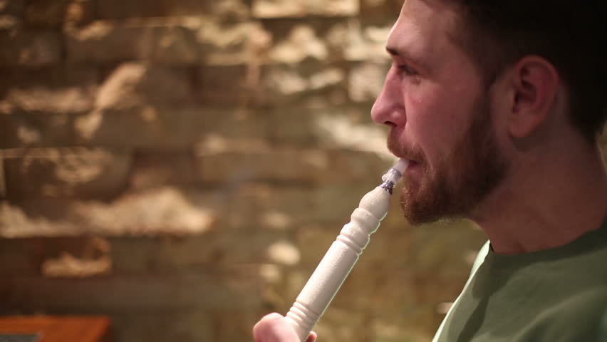 A man with a beard smokes a hookah