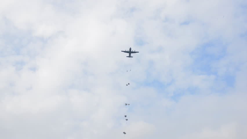 CIRCA 2010s - Ground angle view of paratroopers parachuting to earth from a C-17.