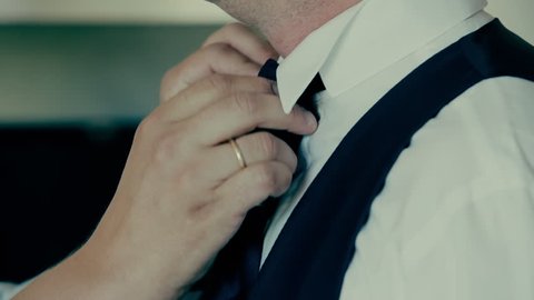Close up hands,best man helps groom with tie.Best man helps the groom with his tie before the wedding.