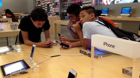 Coquitlam, BC, Canada - March 12, 2015 : People playing with  new iphone inside Apple store in Coquitlam BC Canada.