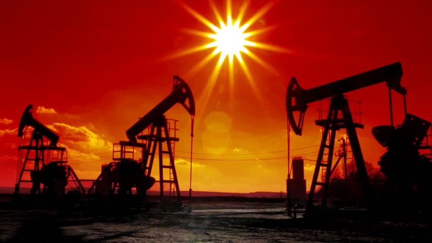 working oil pumps silhouette against sun