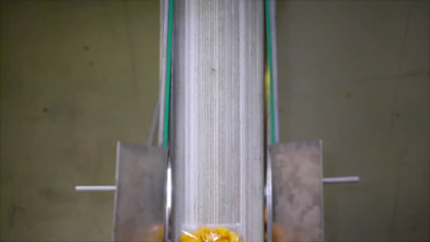 Perpendicular shot of short pasta bags passing on a conveyor belt in a pasta factory. Vibrant colors.