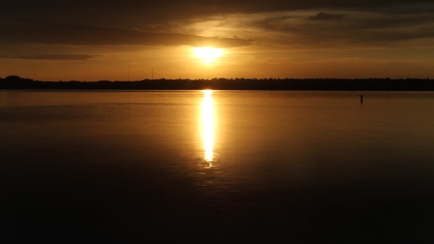 Golden Sunrise reflected in a lake on a cloudy morning, with an ominous feel. HD