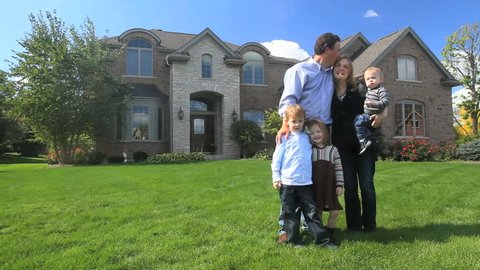 A happy family stands in front of their beautiful brick house 