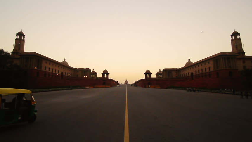 The Rajpath leading to Rashtrapati Bhavan (Presidential Palace) in Delhi, India, at sunset, with rickshaws passing by. Locked down shot from Vijay Chowk.