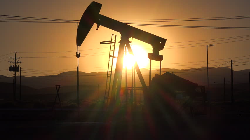 CALIFORNIA - CIRCA 2014 - An oil derrick pumps against a sunset sky.
