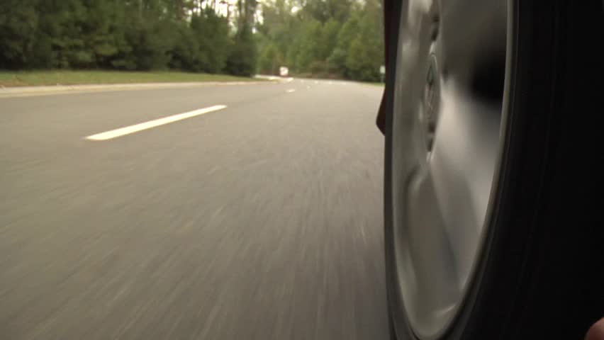 Close up of a rotating wheel and traveling down a road. 