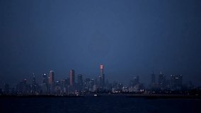 Establishing shot of Melbourne, Victoria, Australia skyline at night with lights twinkling on buildings and traffic. Viewed across the water of Port Phillip Bay.
