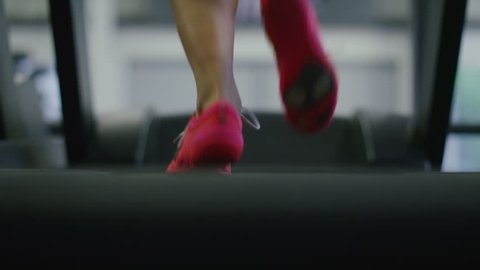 4K Camera tilts up on a young woman running on a treadmill, shot on RED EPIC