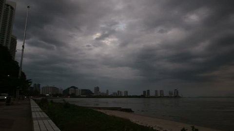 panorama of dramatic stormy dark clouds over skyscrapers from seafront near road