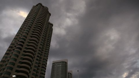 panorama of dramatic stormy dark clouds over skyscrapers from seafront near road
