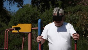 A big man with 3D VR head mounted display in outdoor gym.The multi tasking athlete watches a movie while getting an exercise, gets a phone call