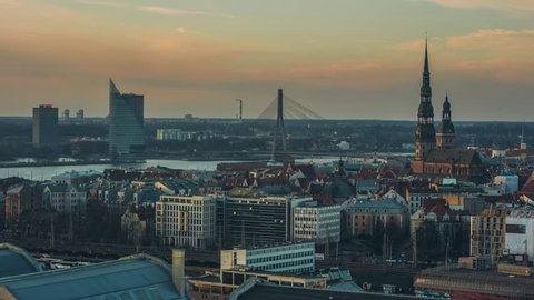 Day to night time lapse of a European City. Medium shot sunset overlooking Riga's Old Town with central train station in the foreground.