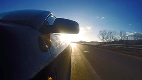 4K Timelapse of sport car front view driving down narrow road toward sun rays at sunset, sunrise. UHD stock video