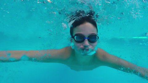 Teen boy swimming underwater in pool. 