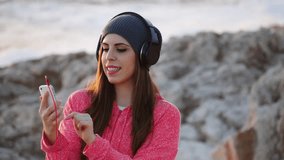 Beautiful young girl with headphones and smartphone in the nature