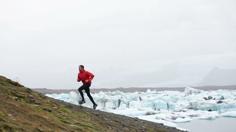 Running man. Trail runner training running uphill in beautiful nature landscape. Fit male athlete jogging and cross country running by icebergs in Jokulsarlon glacial lake in Iceland.