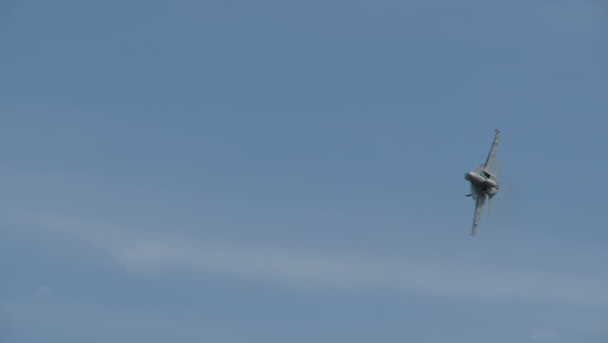 A Boeing Super Hornet in a banking right turn pulling up into a steep climb