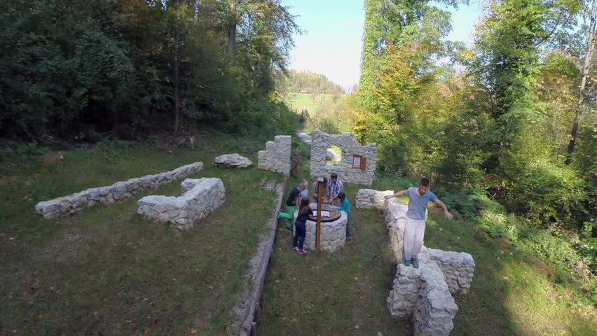 Planing the treasure hunt in the castle ruins . Helicopter camera flaying across the castle ruins where the couple with the kids starting a treasure hunt on the sunny day.