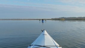 4k Kayakers point of view, in multiple locations, on a river, birds flying in front, through marsh grass, sailboats, with another person. Stock video clip