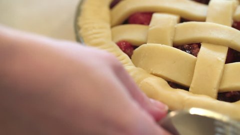 Pastry chef finishes the edges of a cherry pie by pressing in a fork to make a decorative pattern. Stock Video