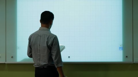 A male teacher drawing a graph using Interactive Projector Board, 21st century learning style.