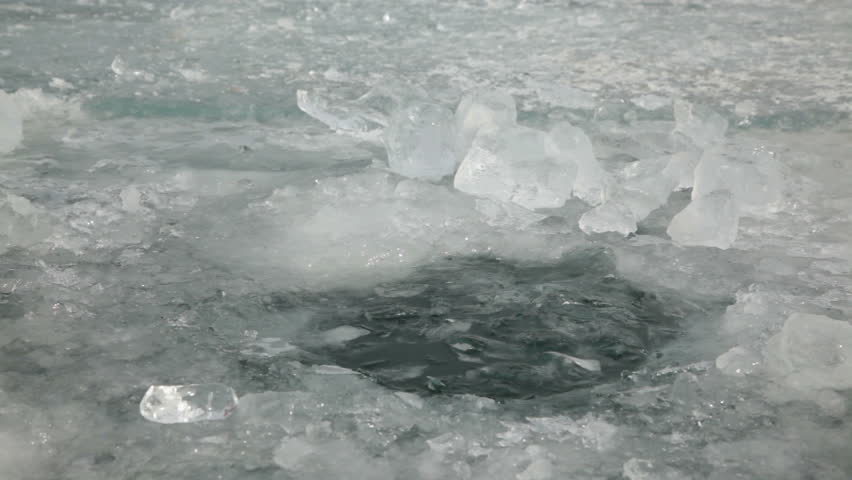 People at the hole in the ice 
Human feels the water in the ice hole 