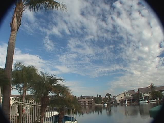 A time-lapse of clouds crossing in two different directions over a lake, with the moon rising in the background.  