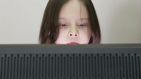 Young girl looking at computer monitor in room, with slider motion