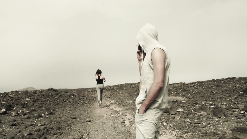 Male jogger smoking cigarette and woman jogging on desert, slow motion shot at 240fps
