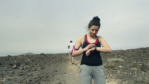Woman with smartwatch and man jogging on desert, slow motion shot at 240fps
