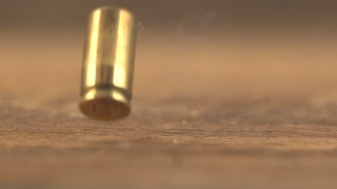 Bullet cases from a 9mm automatic pistol hitting the floor after firing with smoke from casings. Slow-motion, 1/8th natural speed.