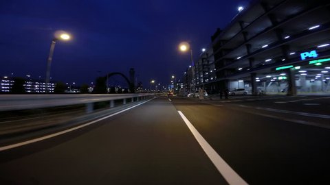 HANEDA AIRPORT, JAPAN - MARCH 19. Driver view nightscape entering arrivals deck at Tokyo International Airport's Terminal 2 and airport road. 