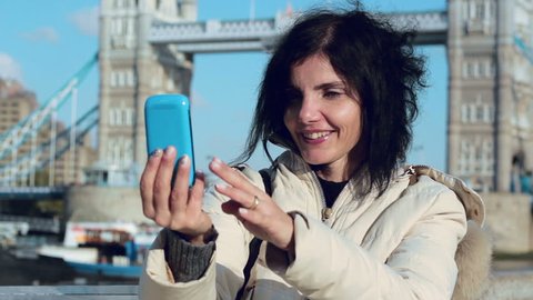 young woman is making a selfie in London with the London Tower bridge