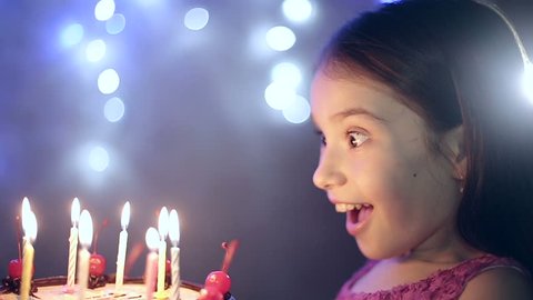 Birthday of the little girl she blows out candles on cake. Slow motion