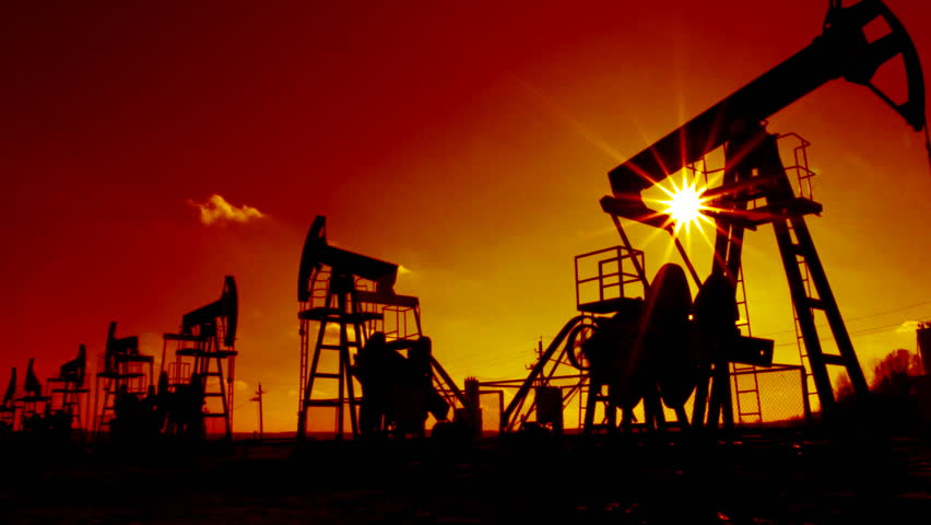 working oil pumps silhouette against sun - timelapse