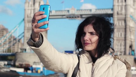 tourist woman is making a selfie with London Tower bridge in background
