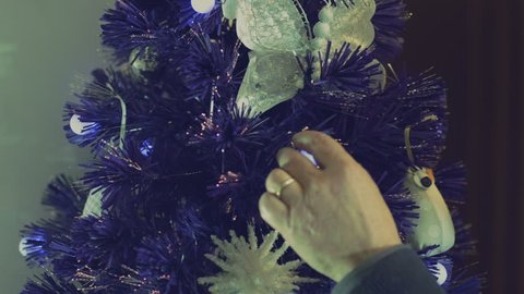 happy lonely man decorates a christmas tree at home